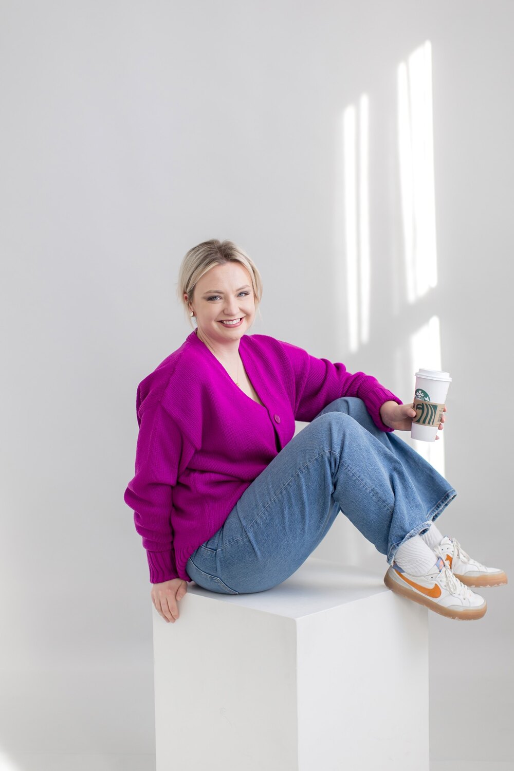 Cat seated in a vivid magenta cardigan